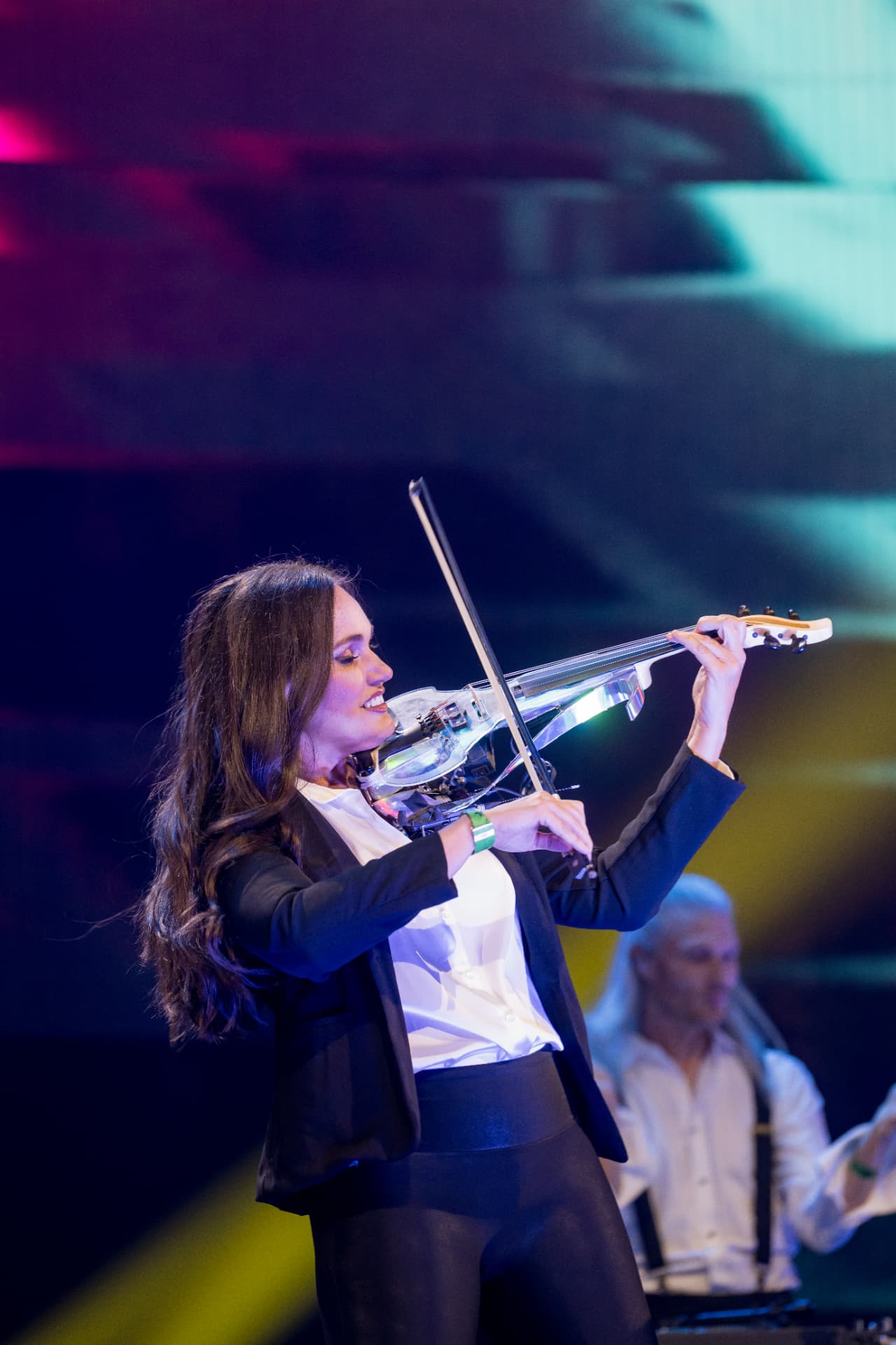 Electric violinist performing under stage lighting at an evening event