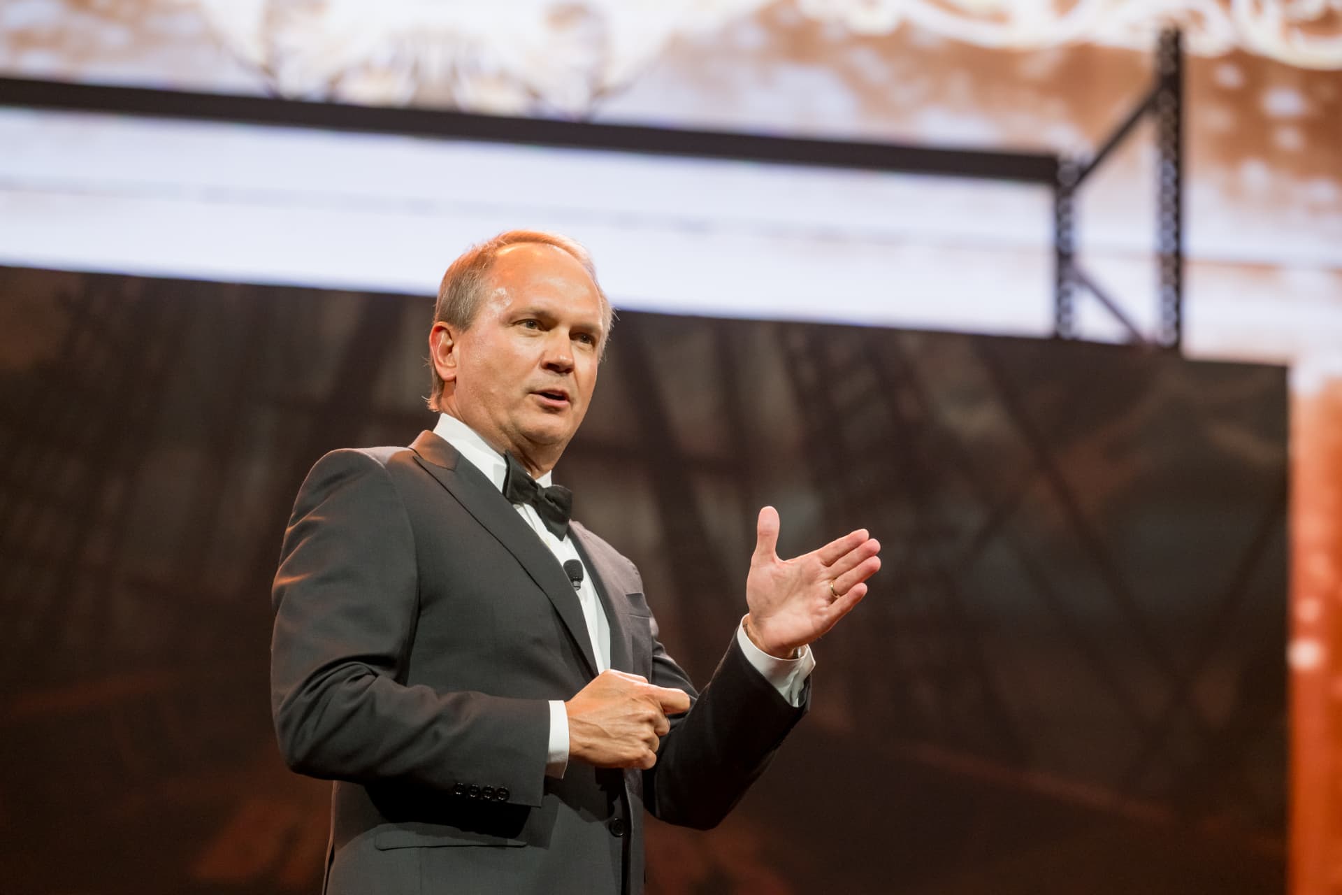 Emcee in a tuxedo addressing guests at a black-tie gala