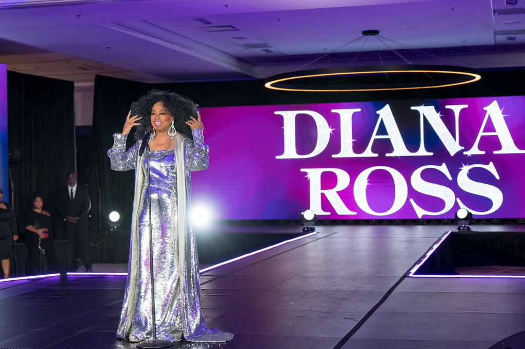 Performer on stage in front of the illuminated marquee screen