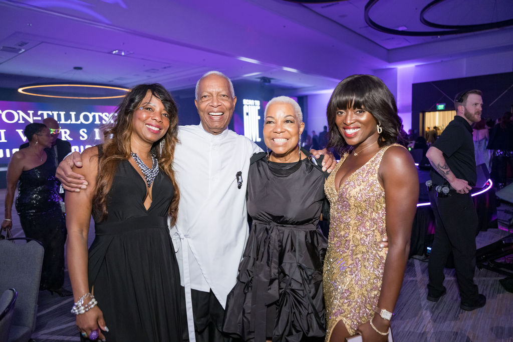 Four guests posing together in front of the gala backdrop