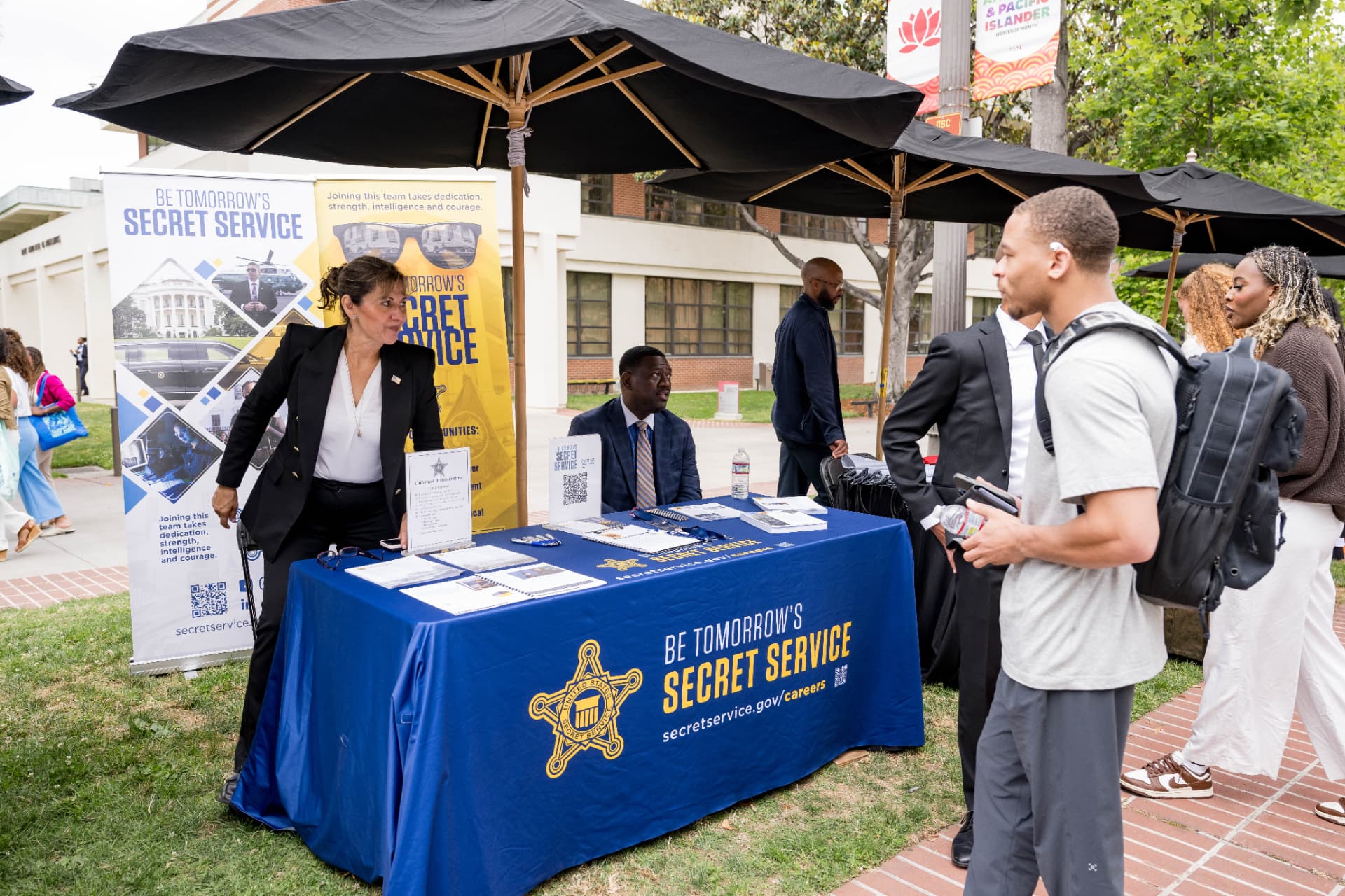 Secret Service recruiting table at an outdoor career expo with attendees stopping by
