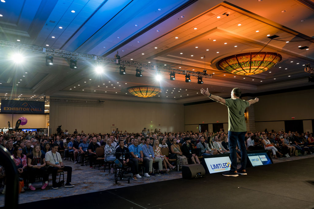 Speaker addressing a packed ballroom from the stage at Limitless Expo