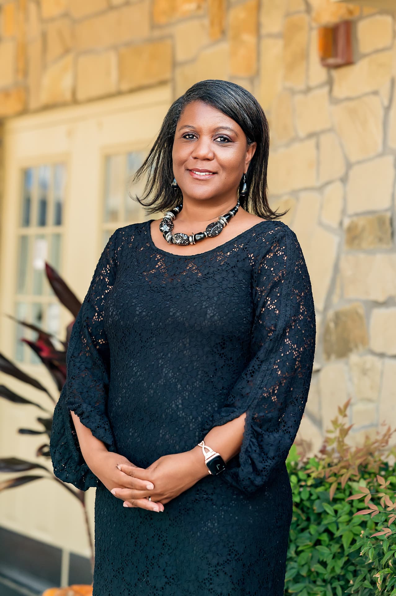 Business portrait of a woman in a black lace dress outside a stone office building