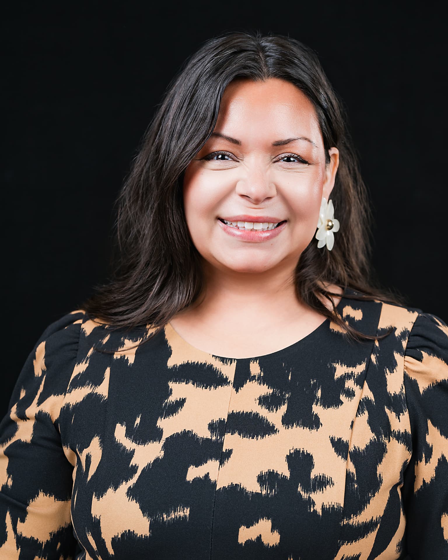 Studio headshot of a smiling professional woman in a patterned dress