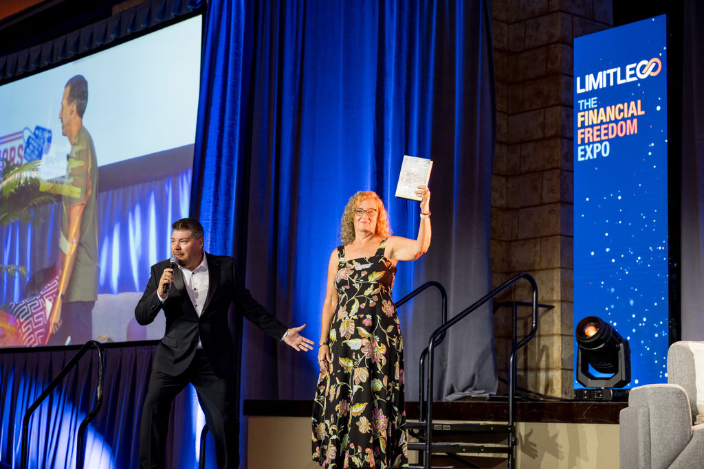 Host and guest presenting a book on stage at Limitless Expo