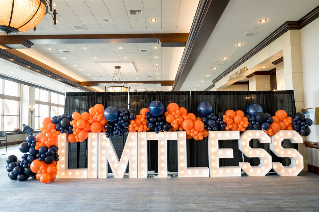 Illuminated LIMITLESS marquee letters with orange and navy balloon display