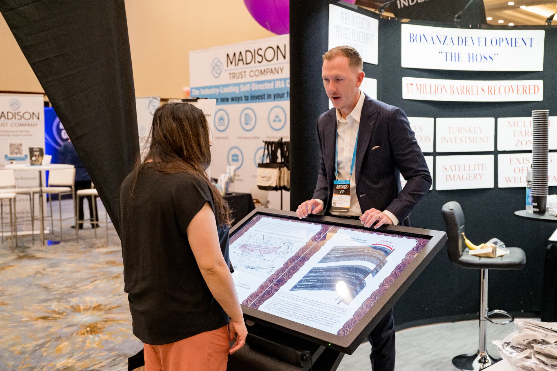 Exhibitor presenting an investment display to an attendee at Limitless Expo