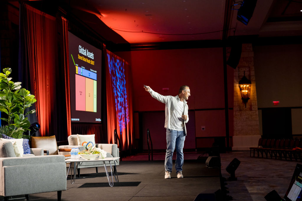Speaker gesturing to a global assets slide on the Limitless Expo stage
