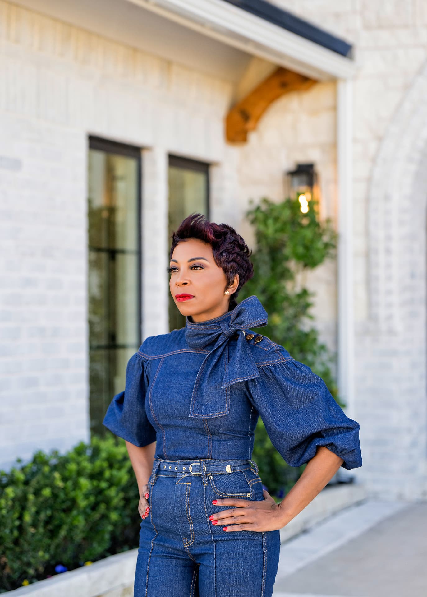 Founder portrait in denim outside a white brick home