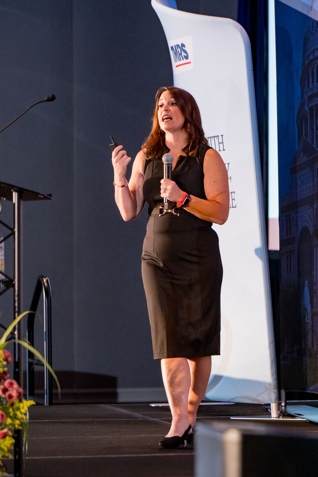 Presenter speaking with a handheld microphone on the TMRS main stage