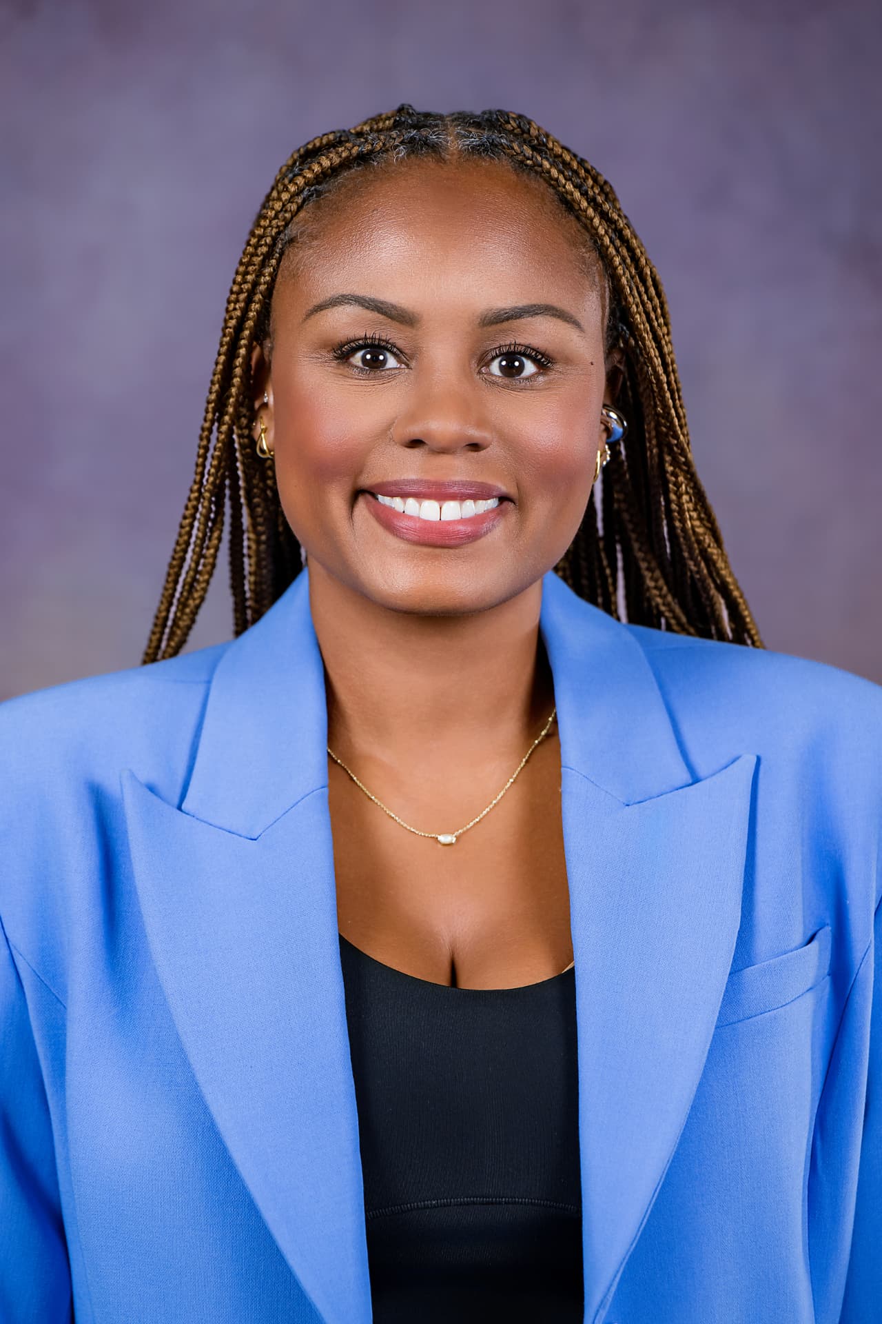 Studio headshot of a smiling woman in a light blue blazer